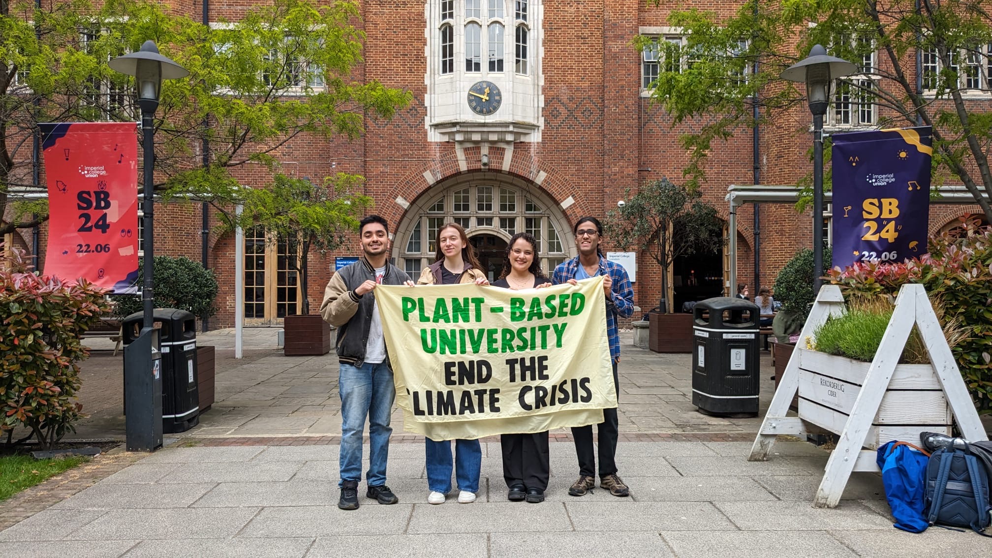 PBU Campaigners stand outside Imperial College Union holding banner which reads "PLANT-BASED UNIVERSITIES END THE CLIMATE CRISIS"